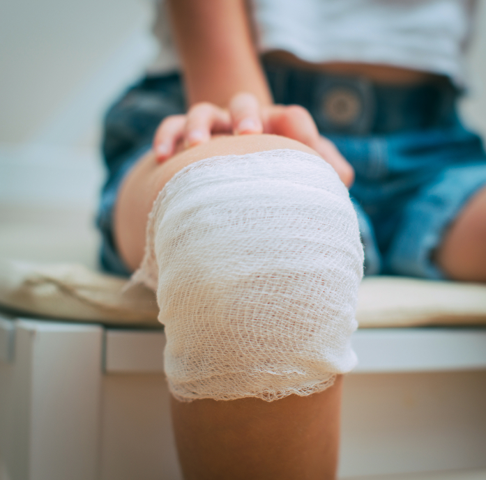 Accident at school Child knee with adhesive and gauze bandage. Child injury at school.
