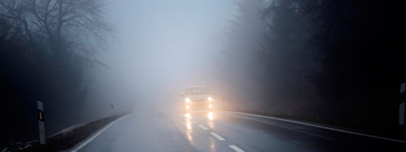 Car driving in fog with fog lights on 