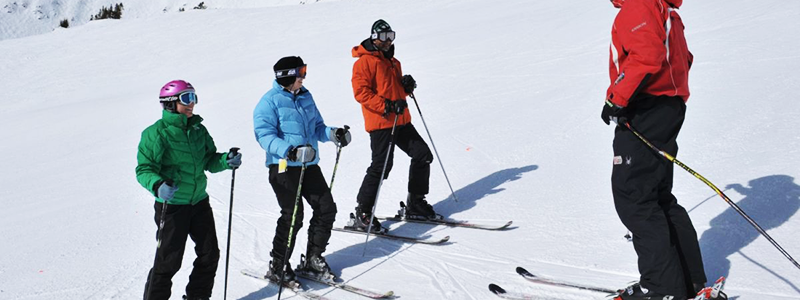 3 people taking a ski lesson from instructor
