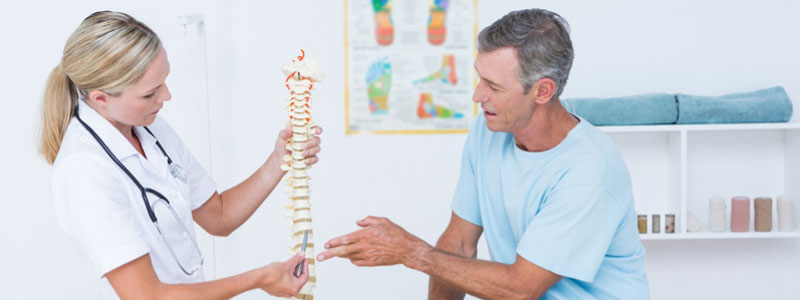 A photo of a patient at the doctor's office being shown the location of a herniated disc injury.